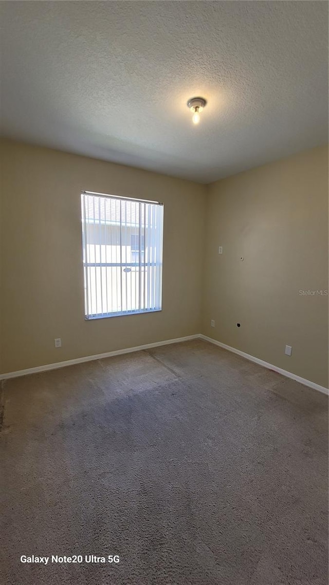 spare room featuring carpet flooring, a textured ceiling, and baseboards