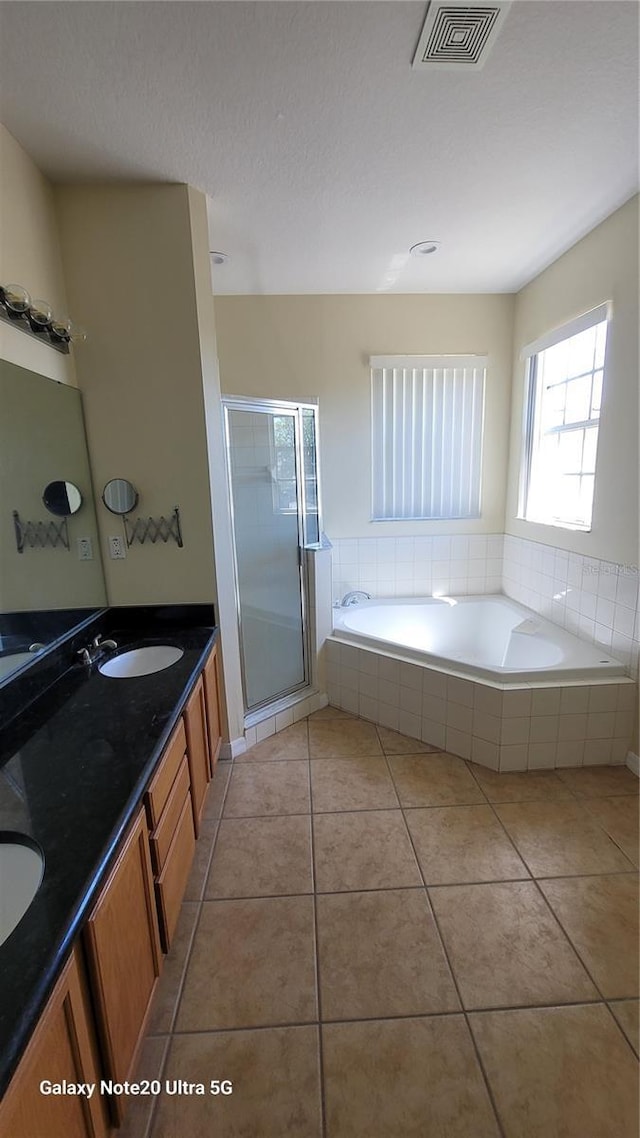 bathroom featuring tile patterned flooring, visible vents, double vanity, a stall shower, and a bath