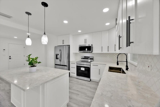 2415 Sutton Rd, Lakeland, FL 33810 - kitchen featuring stainless steel appliances, a sink, backsplash, a center island, and light stone countertops