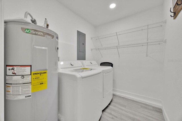 2415 Sutton Rd, Lakeland, FL 33810 - laundry room featuring electric water heater, washing machine and dryer, electric panel, light wood-style floors, and baseboards
