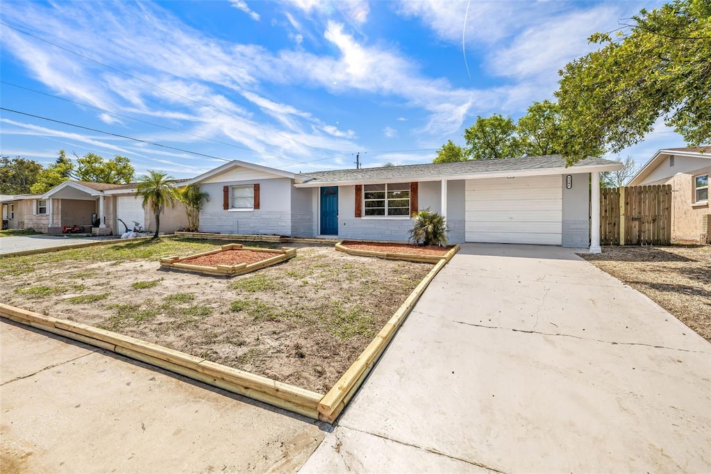 single story home featuring concrete block siding, concrete driveway, fence, and a garage