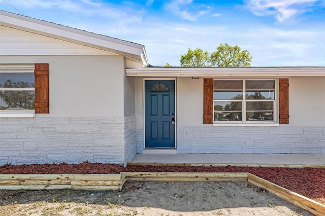 doorway to property featuring stone siding and stucco siding