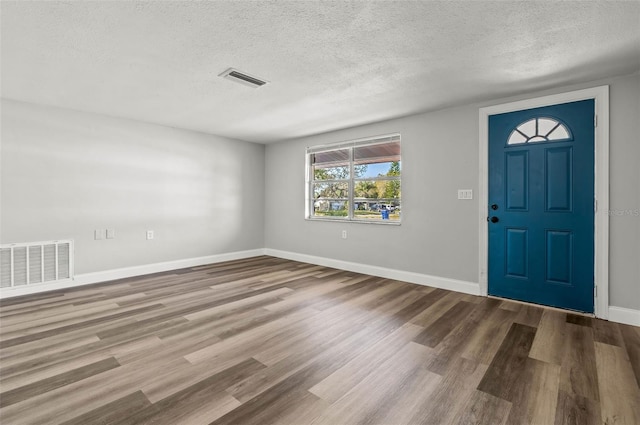 entryway featuring visible vents, baseboards, a textured ceiling, and wood finished floors