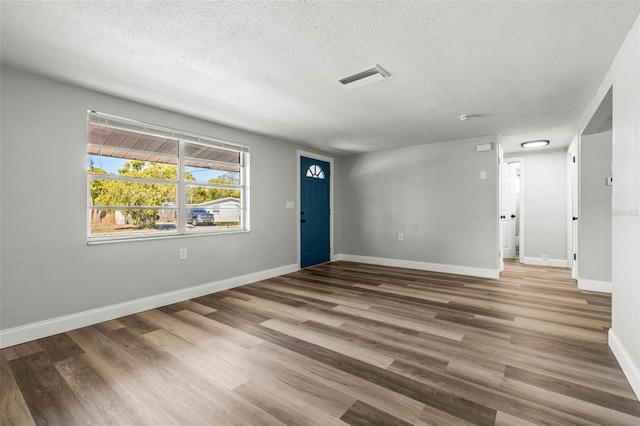 interior space with baseboards, wood finished floors, visible vents, and a textured ceiling