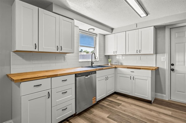 kitchen with stainless steel dishwasher, a sink, light wood-style floors, and butcher block counters