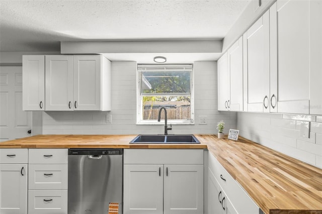 kitchen with stainless steel dishwasher, decorative backsplash, wooden counters, and a sink