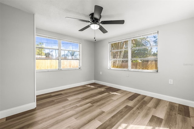 empty room featuring wood finished floors, baseboards, and ceiling fan