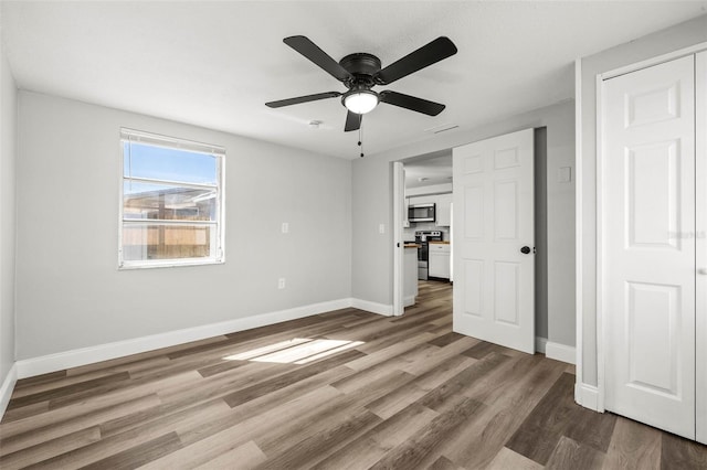 unfurnished bedroom featuring visible vents, wood finished floors, baseboards, and ceiling fan