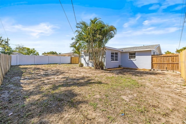 rear view of property featuring stucco siding and a fenced backyard