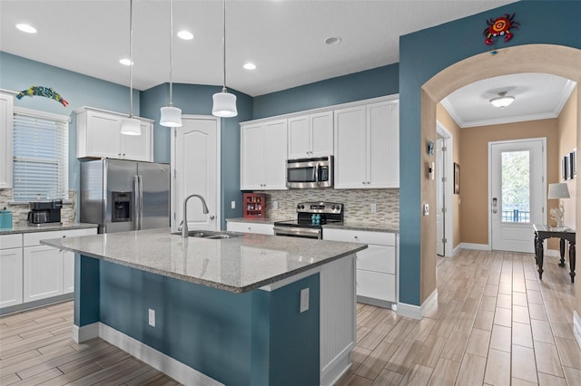 kitchen with wood tiled floor, arched walkways, a sink, appliances with stainless steel finishes, and white cabinetry