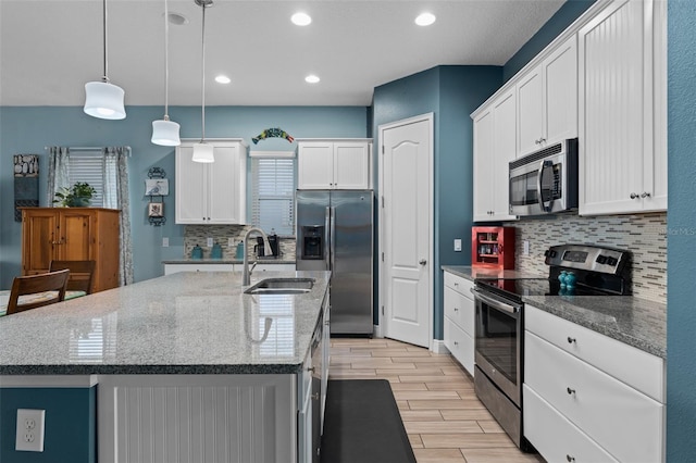 kitchen with white cabinetry, a kitchen island with sink, appliances with stainless steel finishes, and a sink