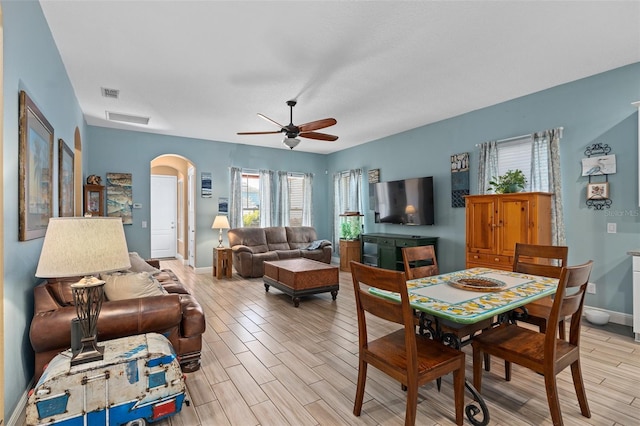 living room with arched walkways, visible vents, ceiling fan, and wood tiled floor