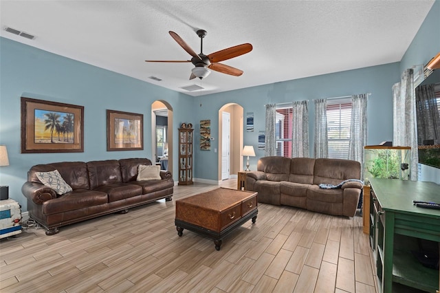 living room featuring visible vents, arched walkways, ceiling fan, and wood tiled floor