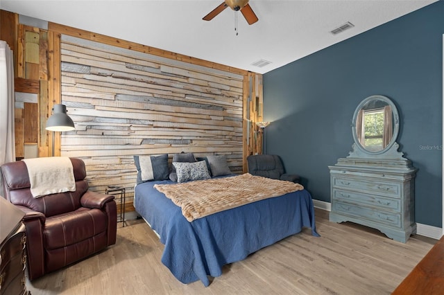 bedroom featuring visible vents, wood walls, an accent wall, and wood finished floors