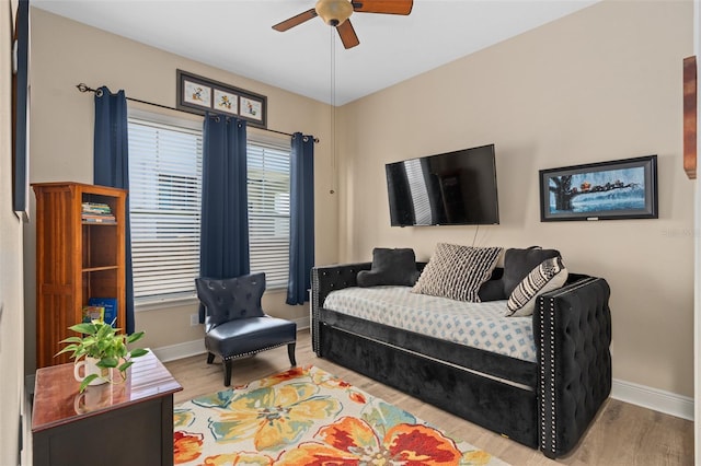 living area featuring baseboards, wood finished floors, and a ceiling fan