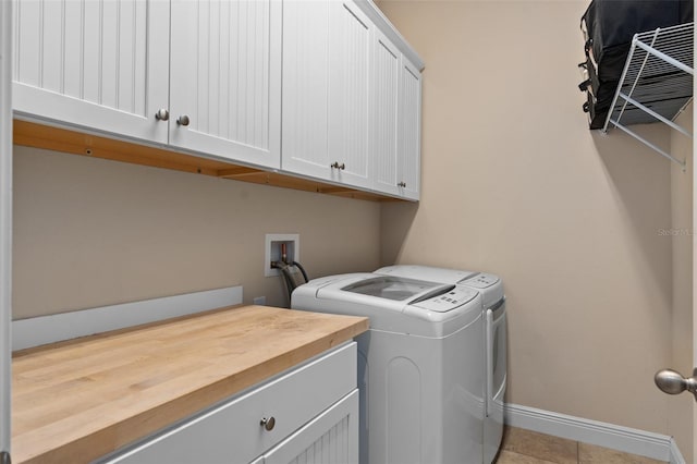 washroom with light tile patterned flooring, washing machine and dryer, cabinet space, and baseboards