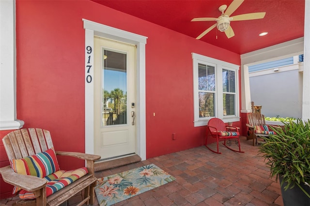 doorway to property with stucco siding, a porch, and a ceiling fan