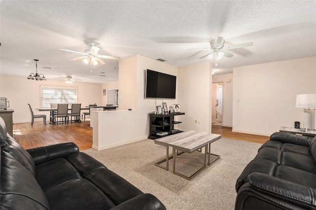 living area featuring visible vents, wood finished floors, a textured ceiling, and ceiling fan