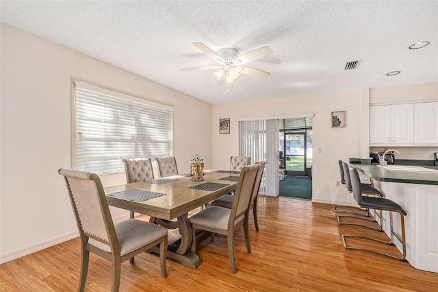 dining room with visible vents, baseboards, light wood-style floors, and ceiling fan