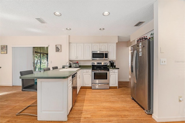 kitchen featuring a sink, stainless steel appliances, visible vents, and a peninsula