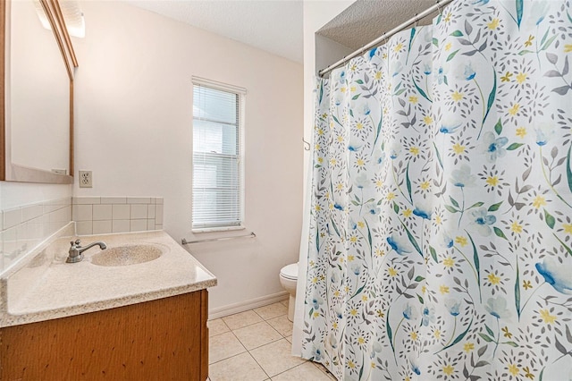 bathroom with vanity, baseboards, tile patterned flooring, a textured ceiling, and toilet