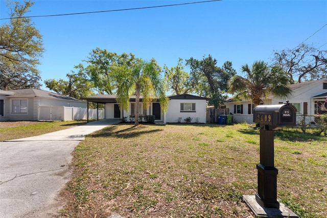 ranch-style home featuring a front yard, a carport, driveway, and fence