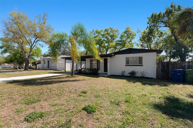 ranch-style house featuring a front yard, stucco siding, fence, and a carport