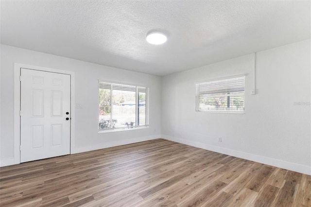 spare room with wood finished floors, baseboards, and a textured ceiling