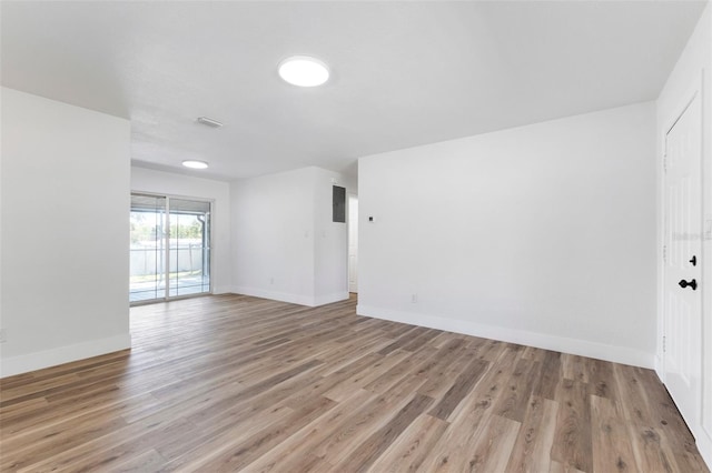 empty room with light wood finished floors, visible vents, and baseboards