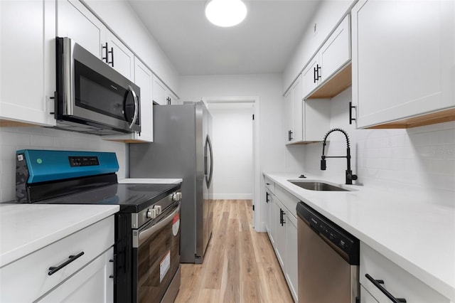 kitchen featuring light countertops, appliances with stainless steel finishes, light wood-style floors, white cabinets, and a sink