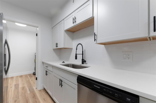 kitchen featuring a sink, light countertops, appliances with stainless steel finishes, light wood-type flooring, and backsplash