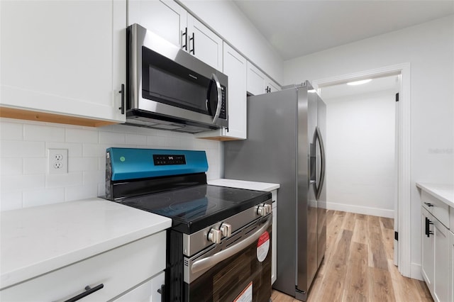 kitchen featuring light wood finished floors, backsplash, light countertops, appliances with stainless steel finishes, and white cabinetry