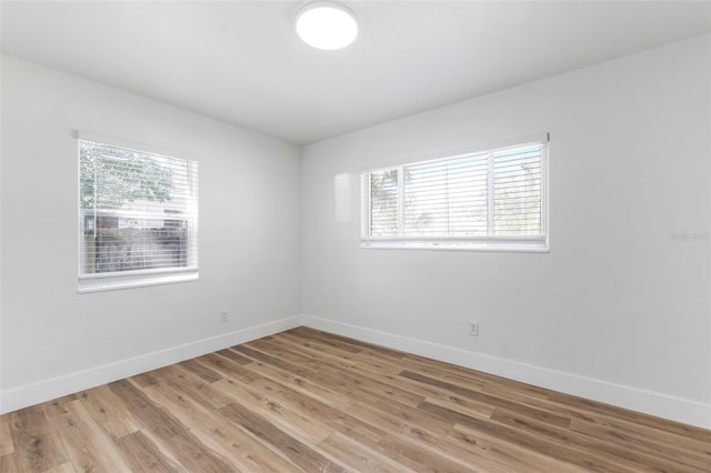 empty room with baseboards, light wood-type flooring, and a wealth of natural light