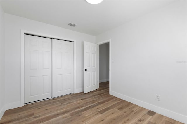 unfurnished bedroom with light wood-style floors, visible vents, a closet, and baseboards