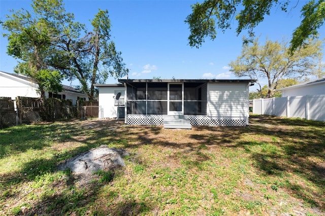 back of house featuring a fenced backyard, a yard, and a sunroom