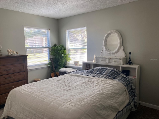 bedroom with a textured ceiling and baseboards