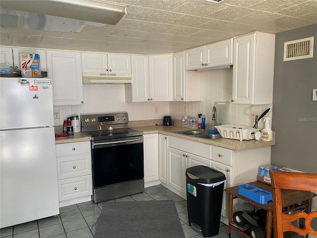 kitchen featuring electric range, visible vents, under cabinet range hood, freestanding refrigerator, and light countertops