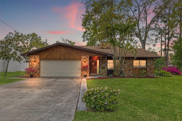 view of front of home with driveway, a front lawn, stone siding, fence, and an attached garage