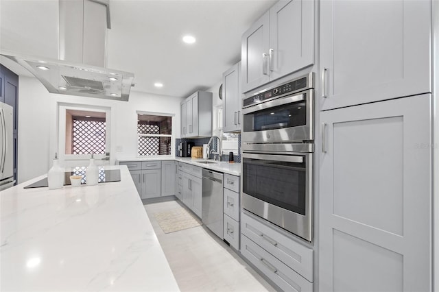 kitchen with island exhaust hood, a sink, recessed lighting, stainless steel appliances, and light stone countertops