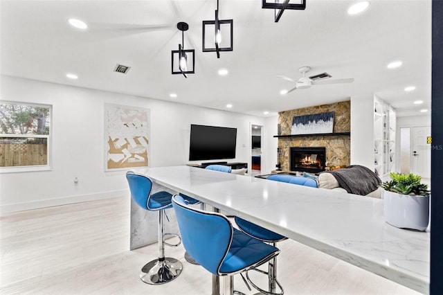 kitchen with light stone counters, visible vents, recessed lighting, and a stone fireplace