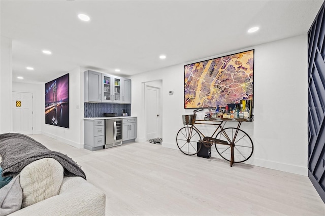 living area with a bar, wine cooler, recessed lighting, and light wood-type flooring