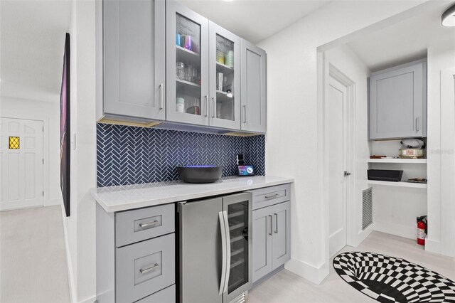 kitchen with light countertops, wine cooler, glass insert cabinets, and gray cabinets