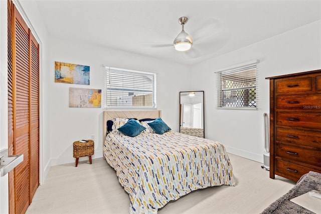 bedroom featuring a ceiling fan, light wood-style flooring, baseboards, and a closet