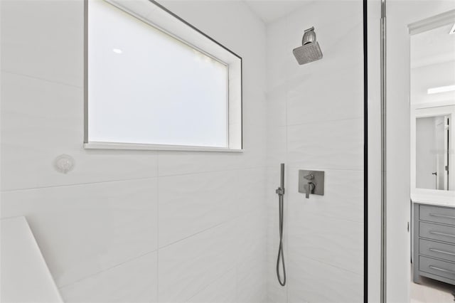 bathroom with vanity and a tile shower