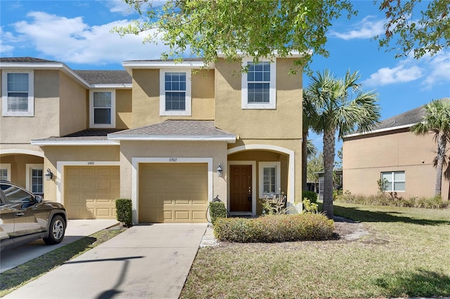 view of property featuring stucco siding, an attached garage, concrete driveway, and a front lawn