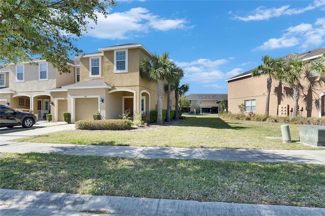 view of front of house with a front yard, concrete driveway, an attached garage, and stucco siding