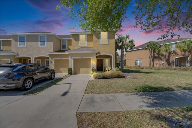 view of property with concrete driveway, an attached garage, a yard, and stucco siding