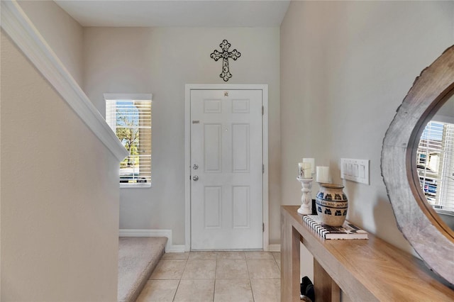 foyer entrance with light tile patterned floors, baseboards, and plenty of natural light