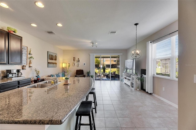 kitchen featuring a sink, visible vents, a breakfast bar, and light tile patterned floors