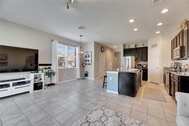 kitchen with a kitchen bar, light stone counters, visible vents, and appliances with stainless steel finishes